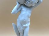 a small statue of a boy holding a vase on his head