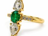 a close up of a gold ring with a green emerald and white diamonds
