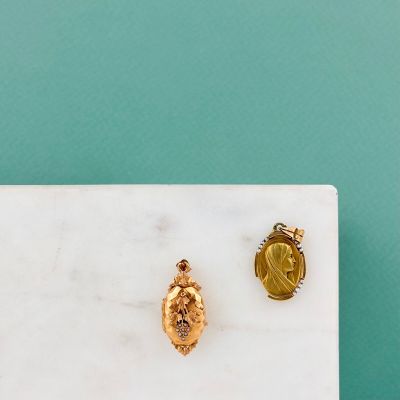 un gros plan sur une paire de boucles d'oreilles en or posées sur une surface en marbre