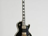 a black electric guitar hanging from a white wall