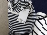 a bag with a tag on it sitting next to a pile of clothes