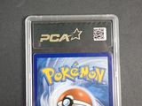 the pokemon card is in a plastic case on a table
