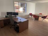 a room with a desk, chairs, and a computer on it
