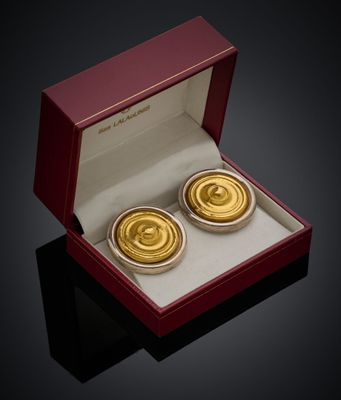 une paire de boutons de manchette plaqués or, présentés dans un coffret rouge posé sur un fond noir