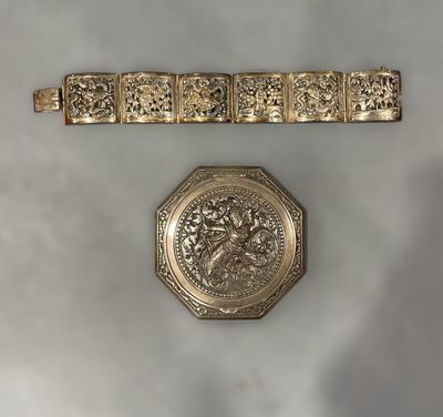 two gold bracelets and a watch on a white surface