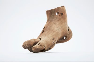 a wooden sculpture of a foot with holes on it