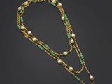 un collier en or orné de perles et de perles de verre vertes