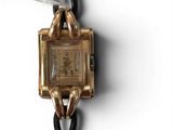 a gold wrist watch with a black leather strap