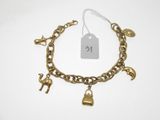 un gros plan d'un bracelet en or orné de breloques sur fond blanc