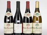 quatre bouteilles de vin sont alignées sur une surface blanche