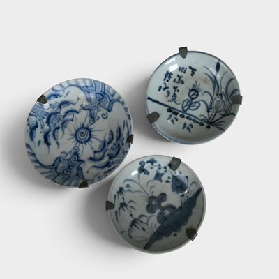 three blue and white bowls with designs on them on a white surface