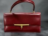 a red leather handbag with a gold handle on a table