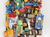 un tas de petites voitures et de camions miniatures posés sur une surface blanche