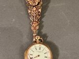 une horloge en or suspendue à une chaîne au mur