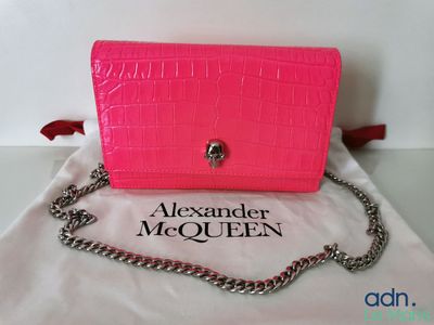un gros plan d'un sac à main rose entouré d'une chaîne