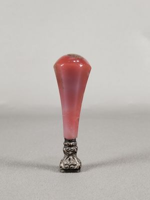 a small red vase with a silver base on a table