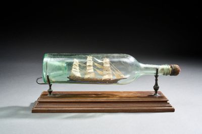 une bouteille en verre contenant un bateau, posée sur un socle en bois