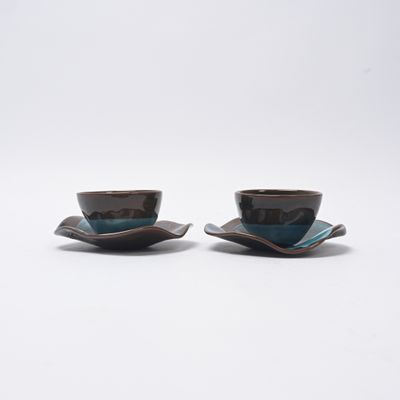 deux tasses posées sur une soucoupe, sur une surface blanche