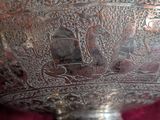 a silver bowl with a design on it on a red cloth