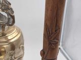 a gold bell with a bird on it next to a wooden stick