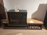 un micro-ondes noir posé sur une étagère, à côté d'une pile de bois