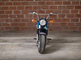 a blue motorcycle parked in front of a brick wall