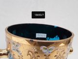 a gold cup with a handle on a white table