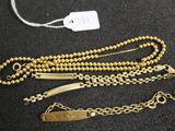 trois bracelets en chaîne dorée et une étiquette sur un fond noir
