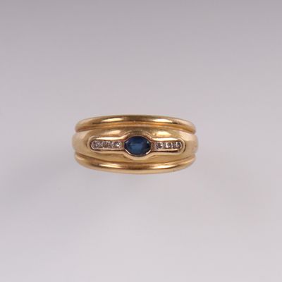 gros plan d'une bague en or avec un saphir et des diamants