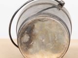 a small metal container with a handle on a table