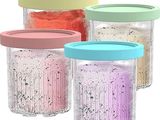 quatre bocaux contenant du sucre de différentes couleurs, posés sur un fond blanc