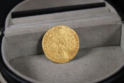 une pièce d'or posée dans une boîte contenant un stylo