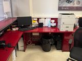 a red desk with a black chair and a computer on it
