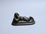 a small bronze statue of a boy laying on the ground