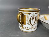 a gold and white cup and saucer on a table