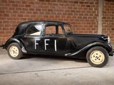 a old black car parked in front of a brick wall