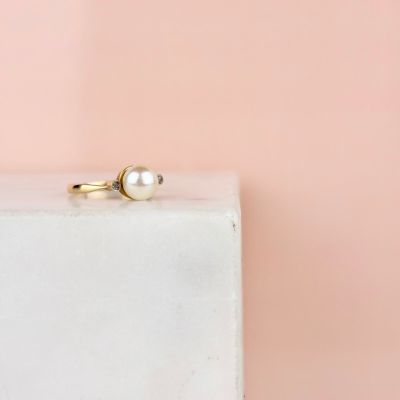 un gros plan d'une bague en perle posée sur un bloc blanc