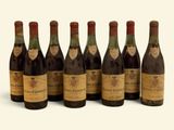 six bottles of wine are lined up in a row on a white surface