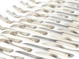 many forks and spoons laid out on a white surface