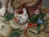 a figurine of a boy with a basket of grapes