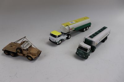 trois camions miniatures posés les uns à côté des autres sur une table