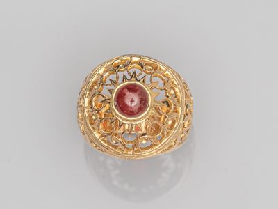 une bague en or sertie d'une pierre rouge entourée de filigrane