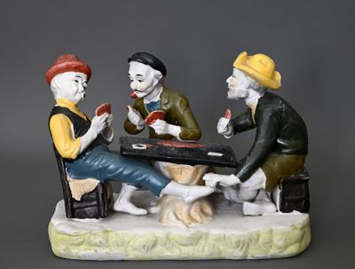 trois figurines représentant des hommes assis à une table en train de jouer aux cartes