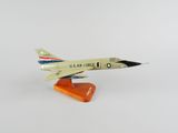 une maquette d'avion de chasse posée sur un socle orange, sur une surface blanche