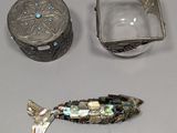 un poisson en argent posé à côté d'une boîte en argent et d'un récipient en argent