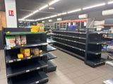 de nombreuses étagères vides dans le magasin, sur lesquelles se trouvent des produits alimentaires