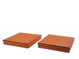 Deux boîtes marron munies d'un couvercle sont posées côte à côte sur une surface blanche.
