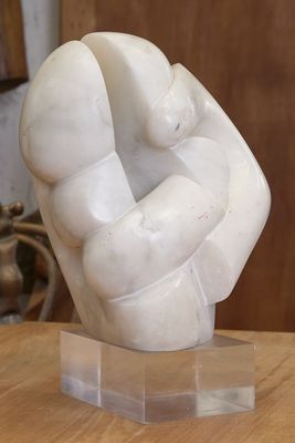 une sculpture en marbre représentant un poing, posée sur un socle transparent