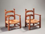 pair of antique wooden chairs with woven seats on a grey background