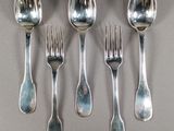 six cuillères et une fourchette sont disposées en rang sur une table